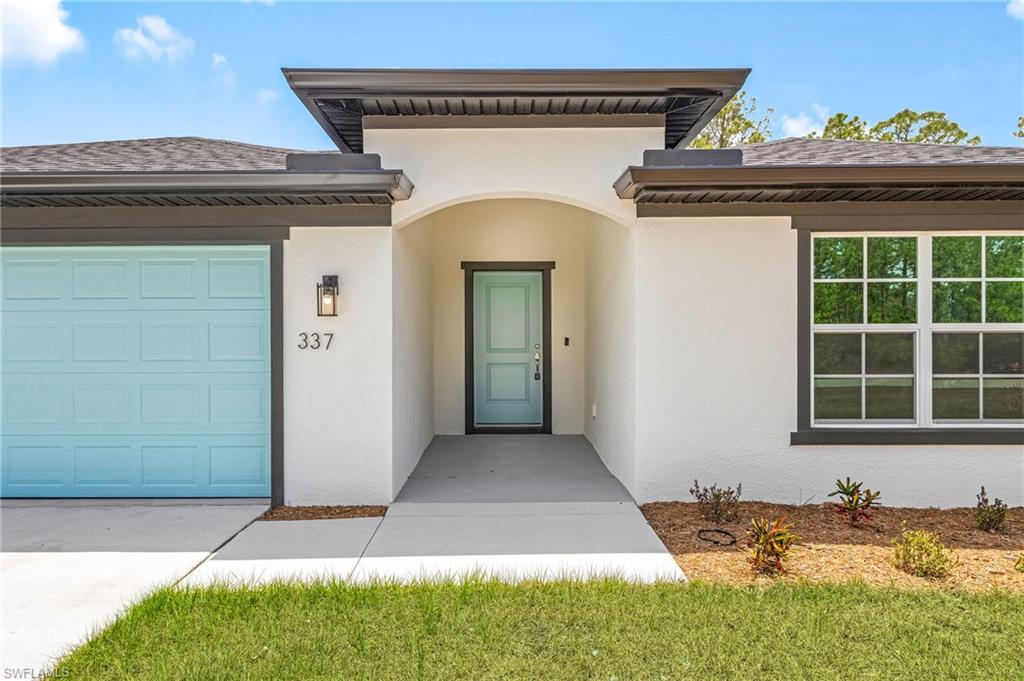 Entrance to property featuring stucco siding, an attached garage, and driveway