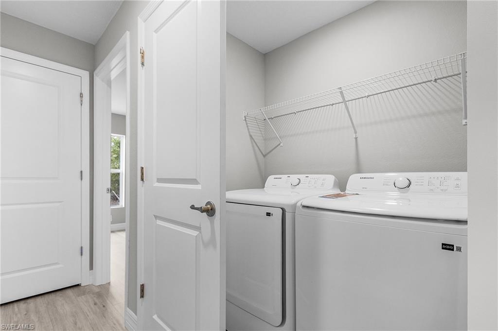 Clothes washing area featuring light wood-style floors and washing machine and clothes dryer