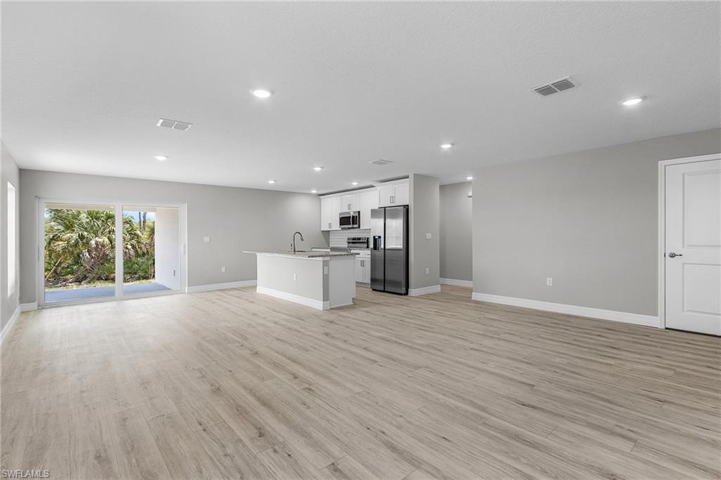 Unfurnished living room with baseboards, recessed lighting, light wood-type flooring, and a sink