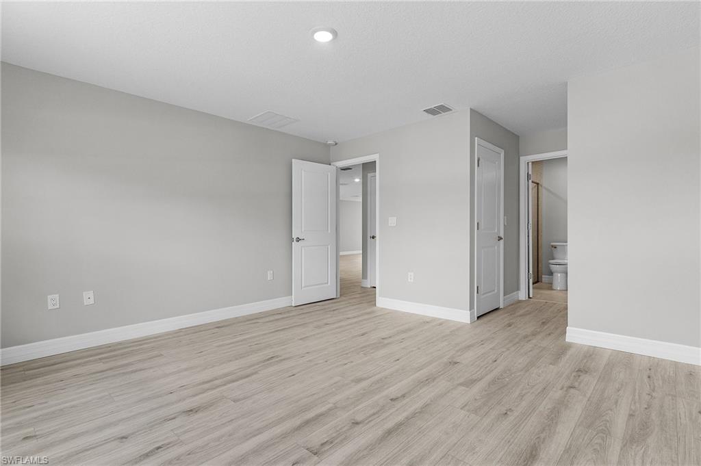 Unfurnished bedroom with light wood-style floors, baseboards, recessed lighting, and connected bathroom