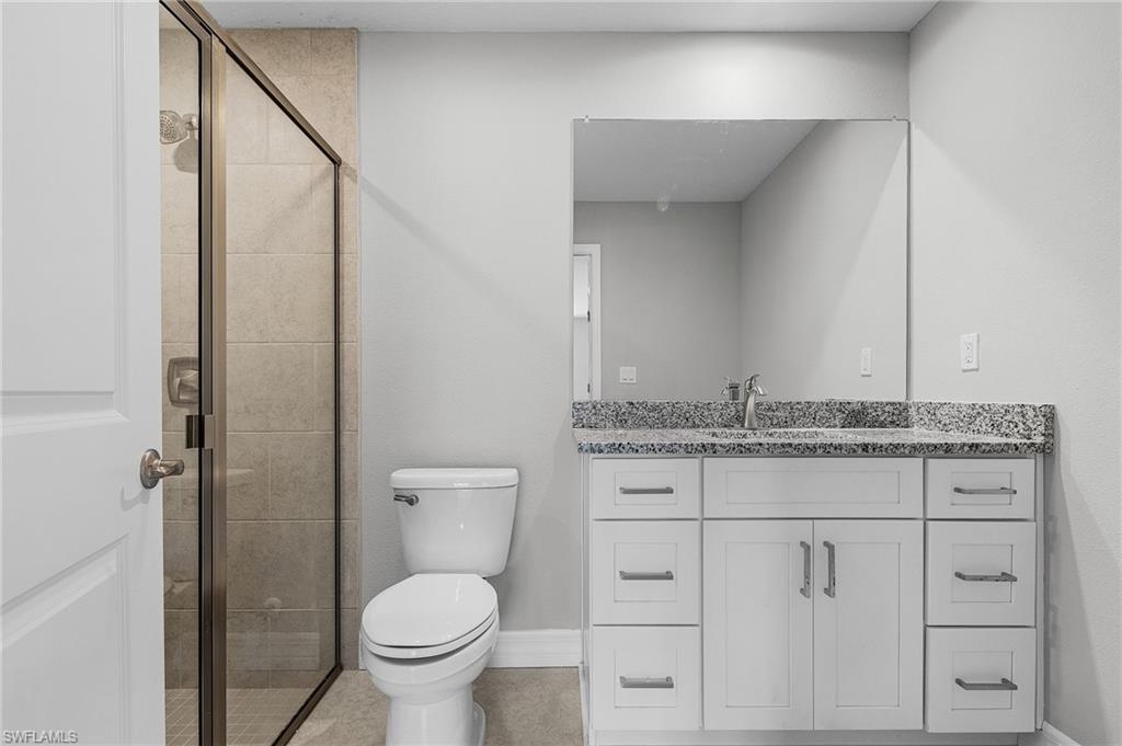 Bathroom featuring a shower stall, toilet, and vanity