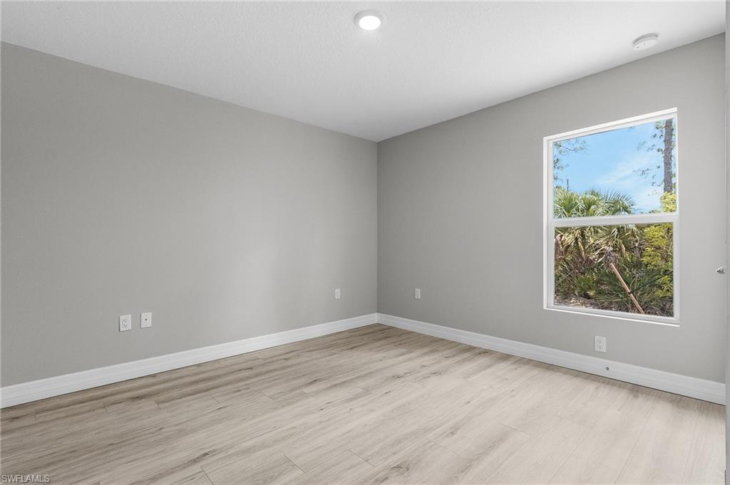 Spare room with light wood-style floors, a smoke detector, and baseboards