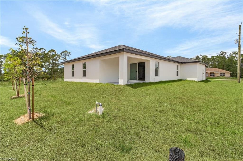 Back of house featuring a lawn and stucco siding