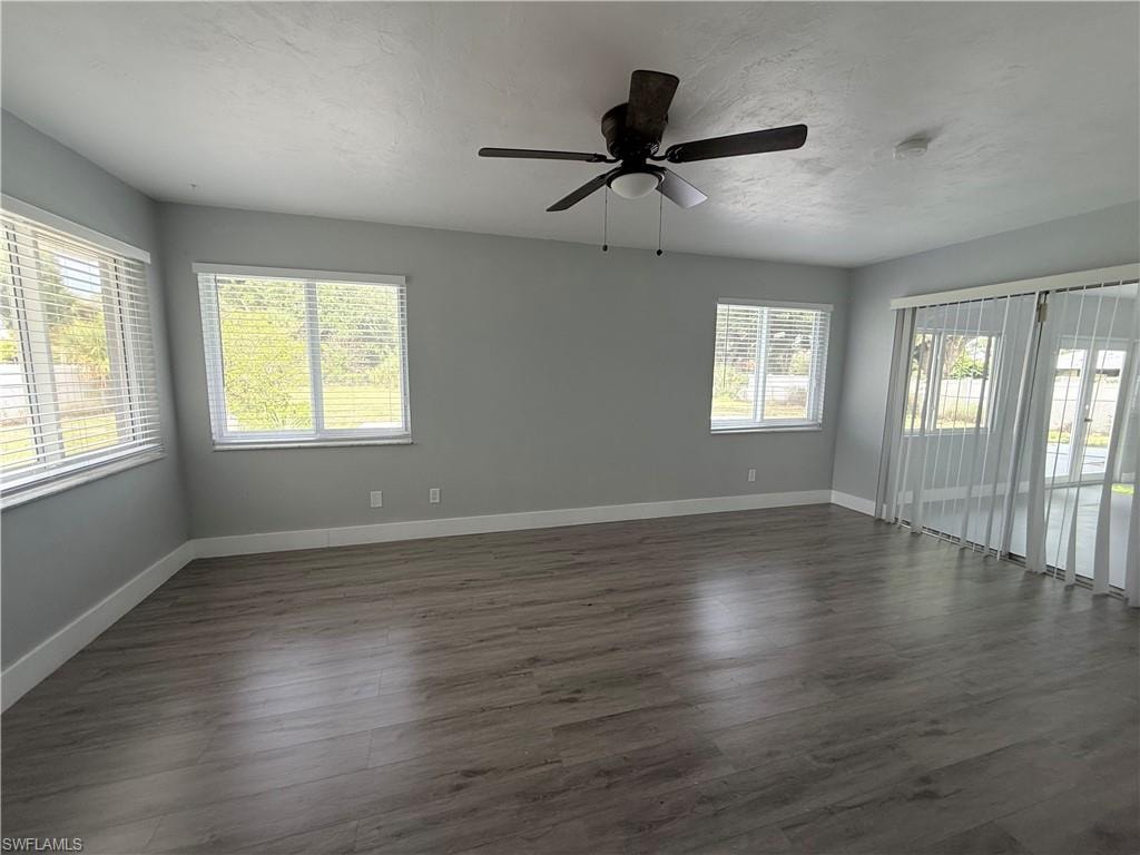 Unfurnished room with dark wood-type flooring, ceiling fan, and a smoke detector