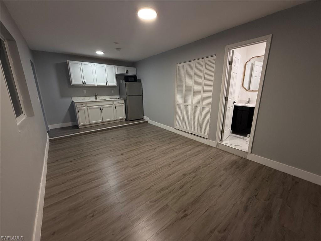 Unfurnished living room featuring dark wood-type flooring and recessed lighting