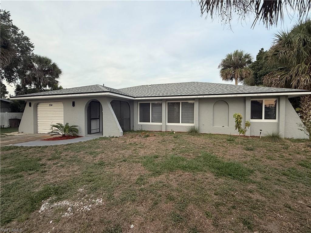 Ranch-style home featuring an attached garage, stucco siding, and a front lawn