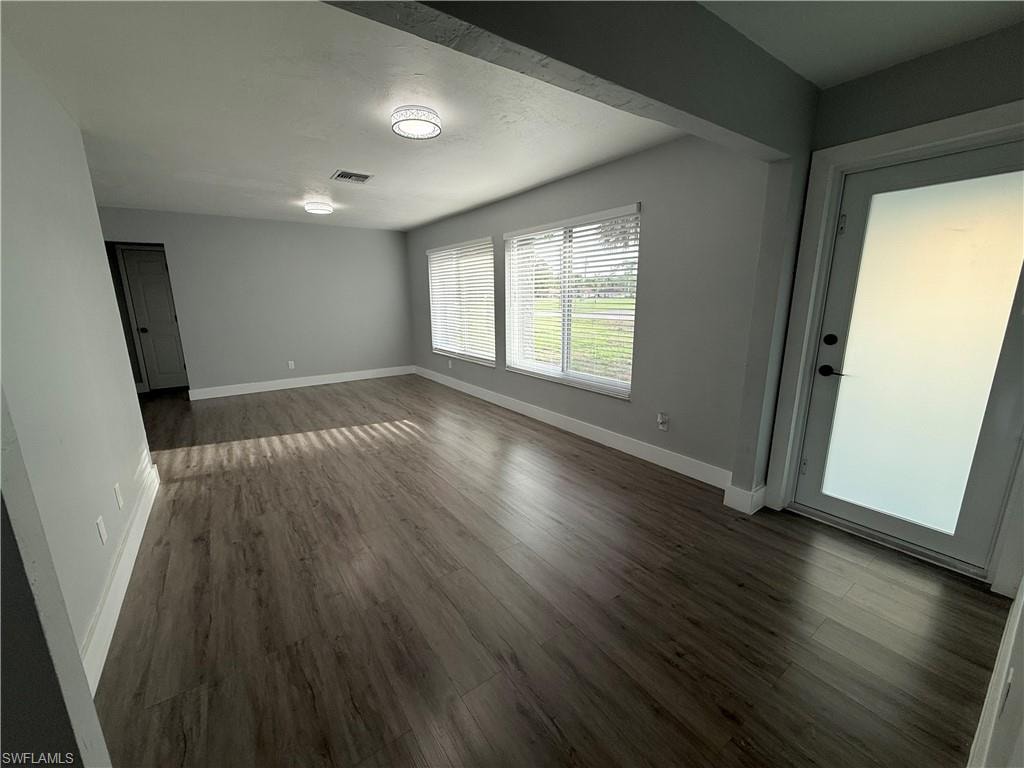 Unfurnished room featuring dark wood-style floors and baseboards