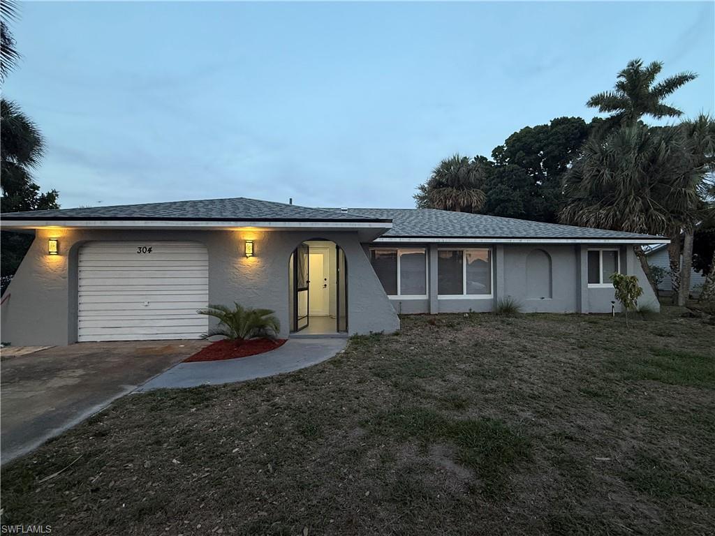 View of front of property with a garage, stucco siding, and driveway