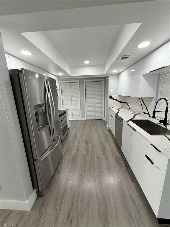 Kitchen featuring modern cabinets, refrigerator, white cabinetry, light wood-style floors, and recessed lighting