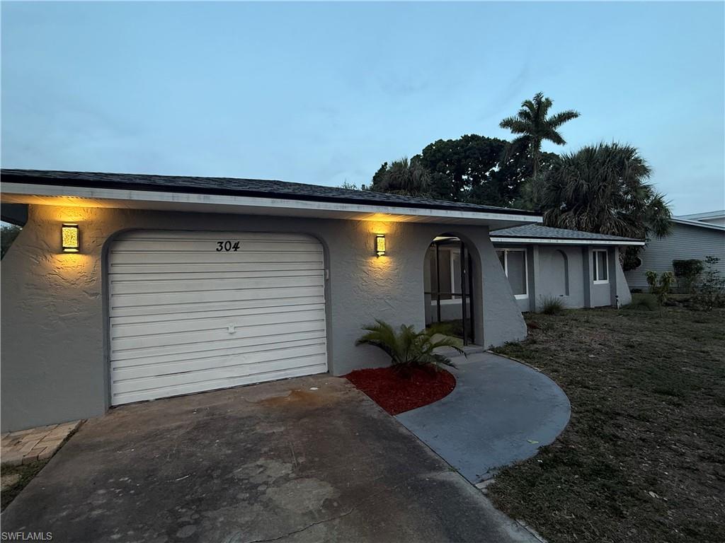 View of front of property with driveway, stucco siding, and a garage