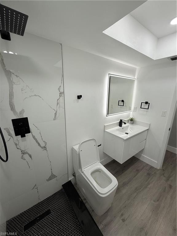Bathroom with a marble finish shower, wood finished floors, and vanity