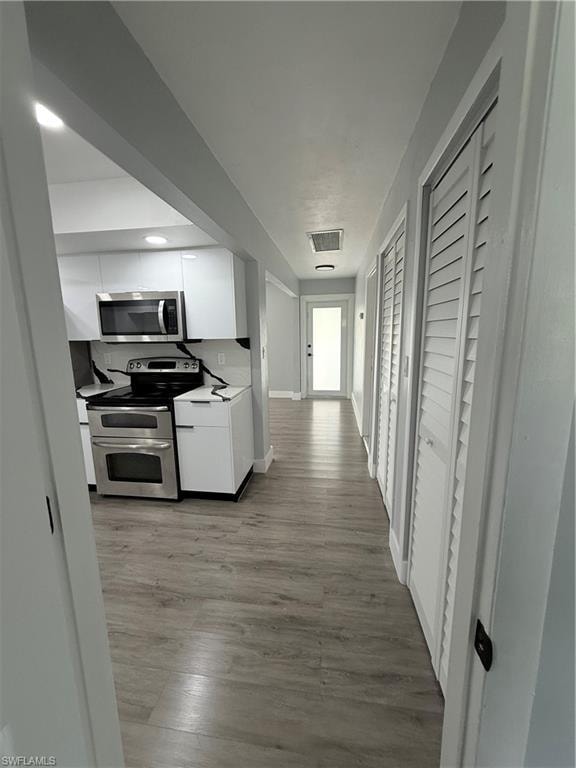 Kitchen with range, white cabinets, light wood-style floors, and light countertops