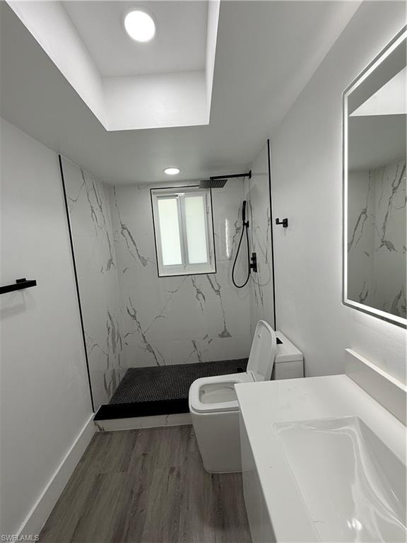 Bathroom with a marble finish shower, wood finished floors, and vanity