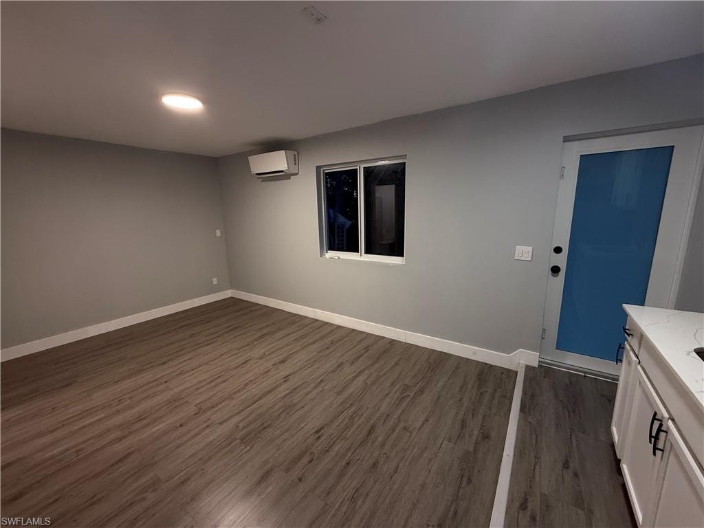 Spare room featuring a wall mounted AC and dark wood-style floors