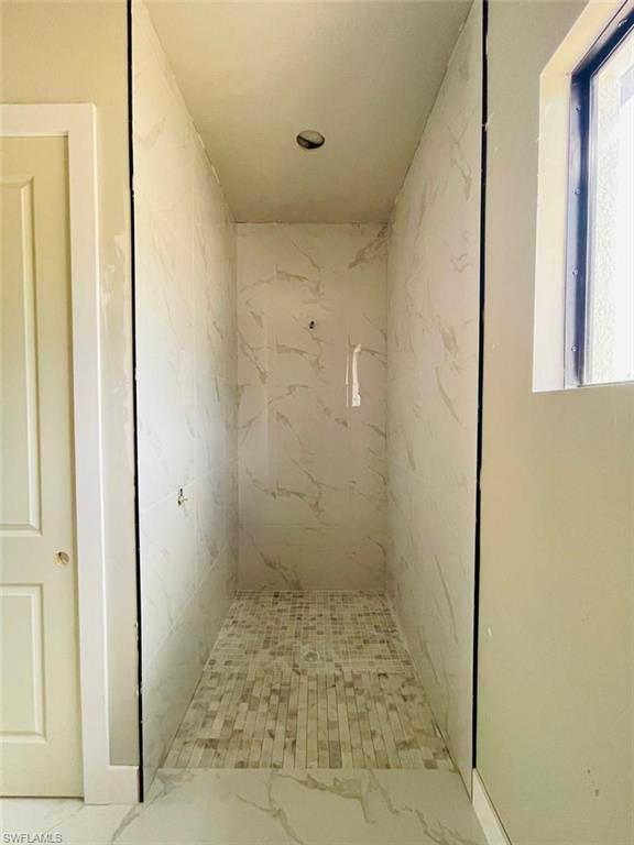 Full bathroom featuring marble look tile flooring and a marble finish shower