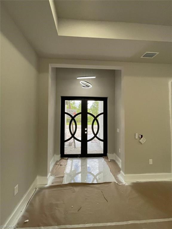 Foyer featuring french doors and a tray ceiling