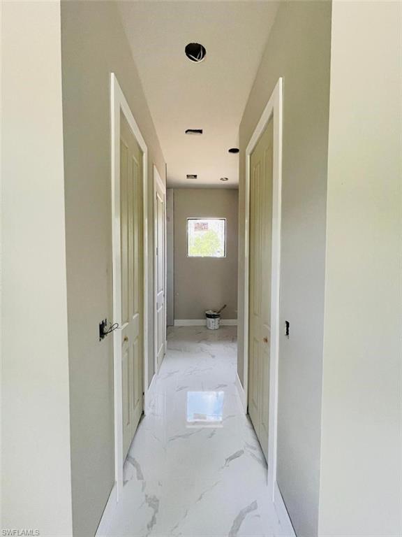 Hall with light marble finish flooring and baseboards