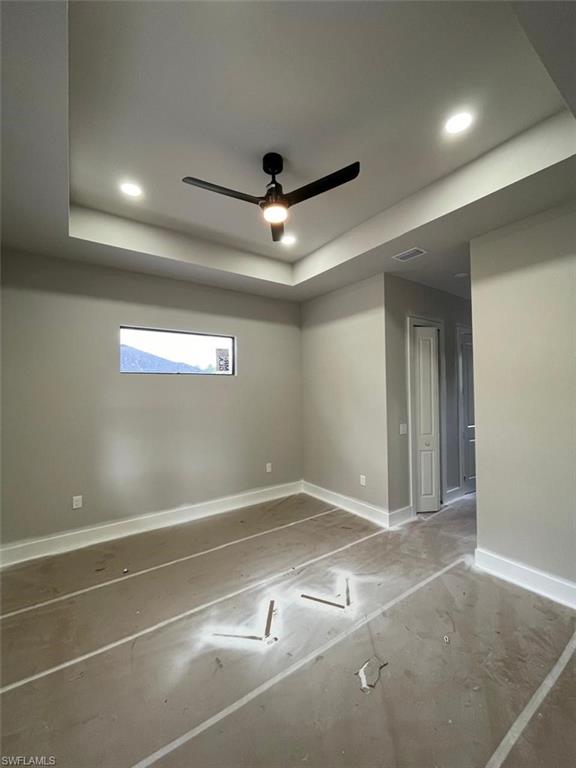 Empty room with ceiling fan, recessed lighting, and a raised ceiling