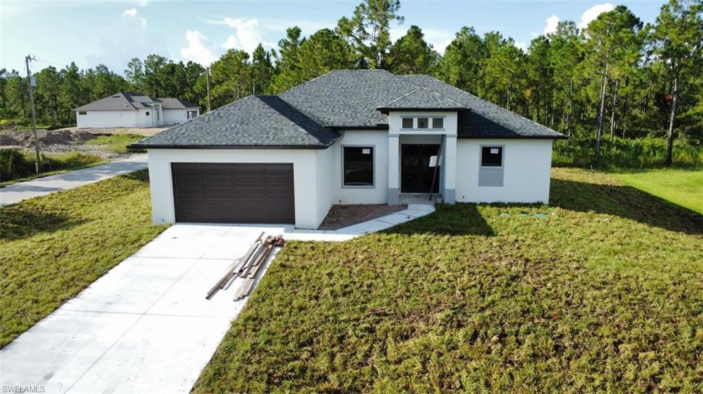 View of front of home featuring a front yard, stucco siding, concrete driveway, a garage, and roof with shingles