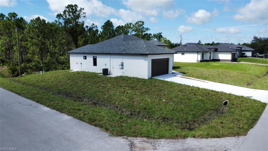 View of side of property featuring a garage, stucco siding, and driveway