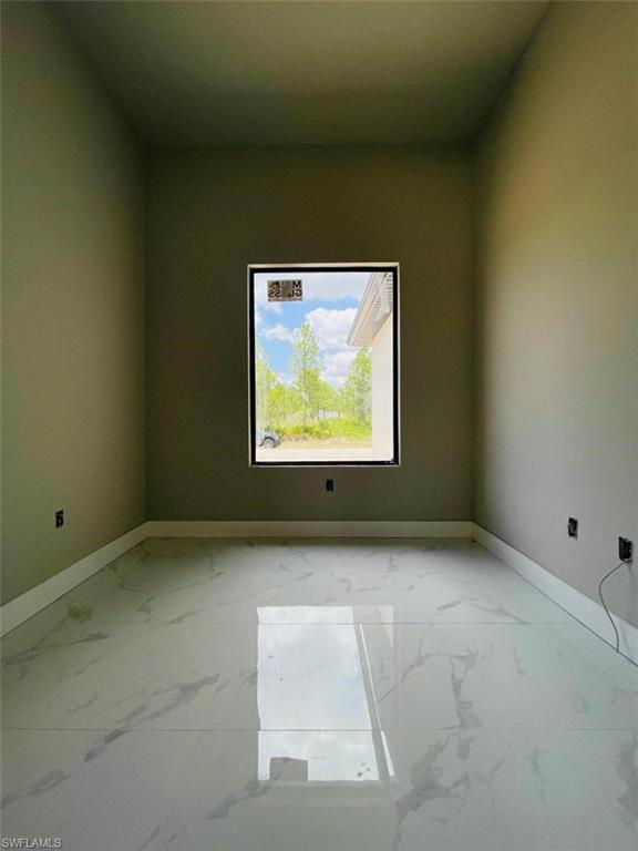 Empty room with marble look tile flooring and baseboards