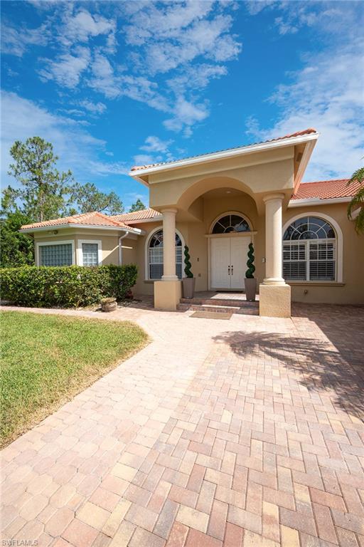 View of front facade featuring a tile roof, stucco siding, and a front lawn