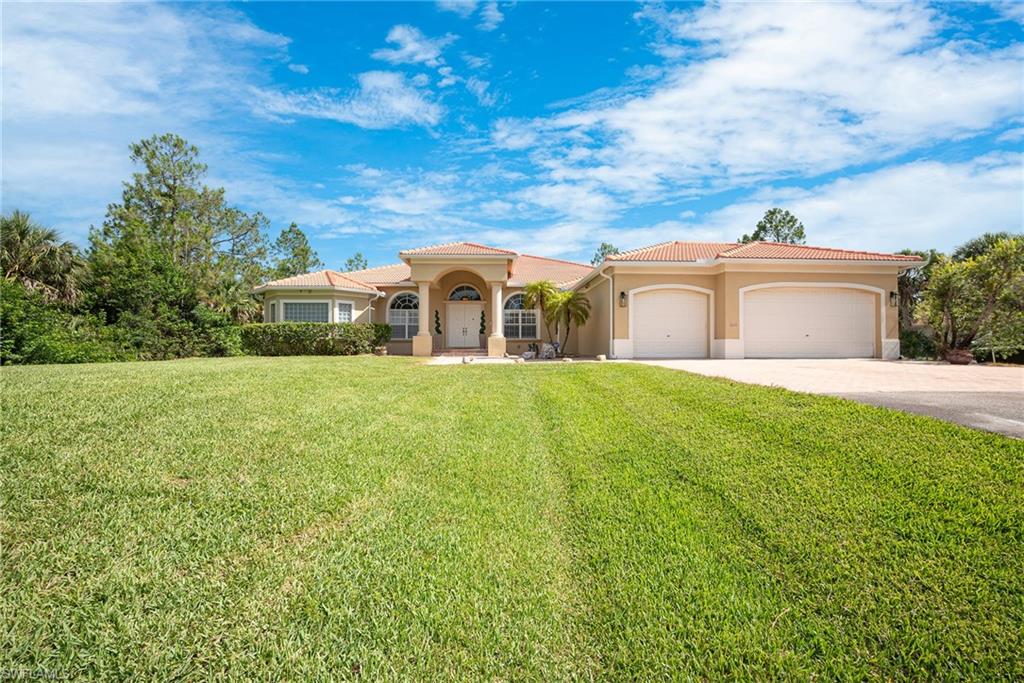 Mediterranean / spanish house with a garage, driveway, stucco siding, a front lawn, and a tiled roof