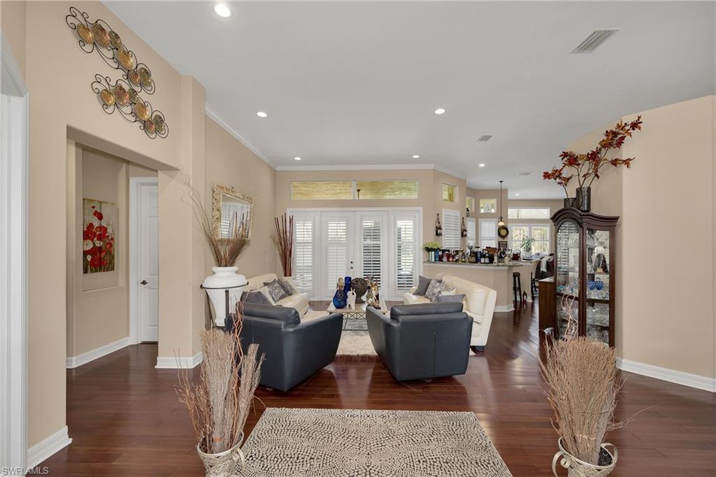 Living room featuring dark wood-style floors, recessed lighting, and ornamental molding