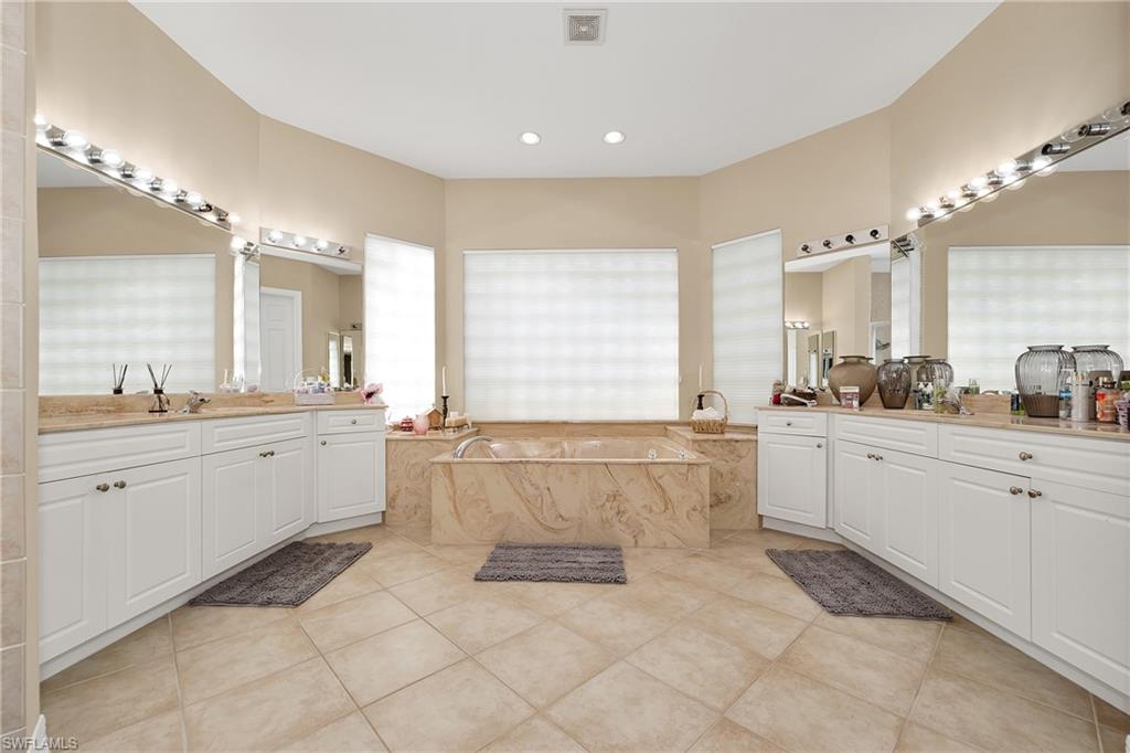 Full bathroom featuring tile patterned floors, a bath, two vanities, and recessed lighting