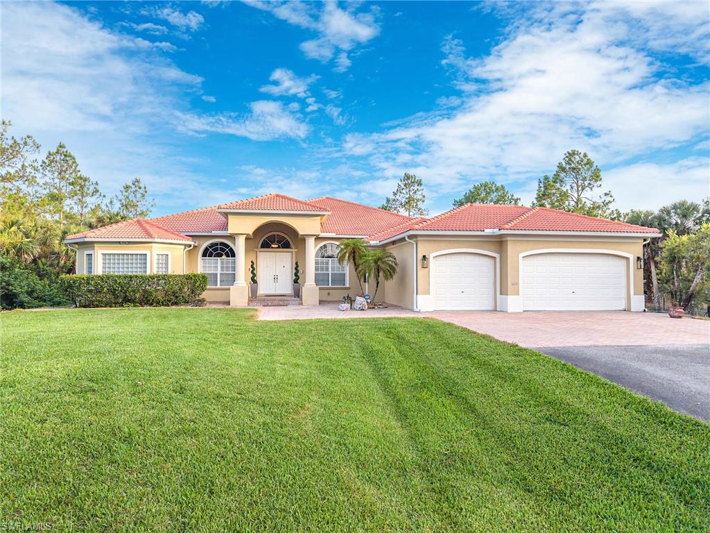 Mediterranean / spanish-style house featuring stucco siding, a garage, asphalt driveway, a front lawn, and a tiled roof