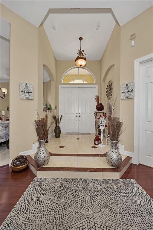 Entrance foyer featuring a chandelier, wood finished floors, and arched walkways