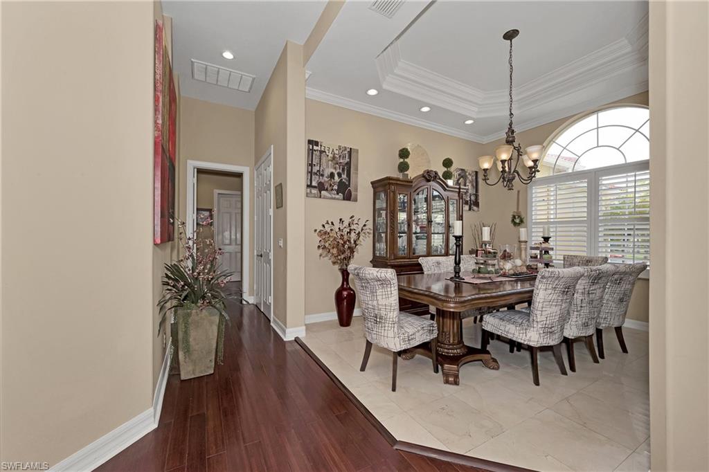 Dining space featuring a chandelier, recessed lighting, crown molding, a raised ceiling, and wood finished floors
