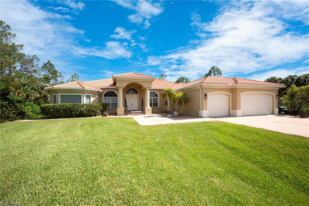 Mediterranean / spanish home with stucco siding, an attached garage, driveway, a front yard, and a tile roof