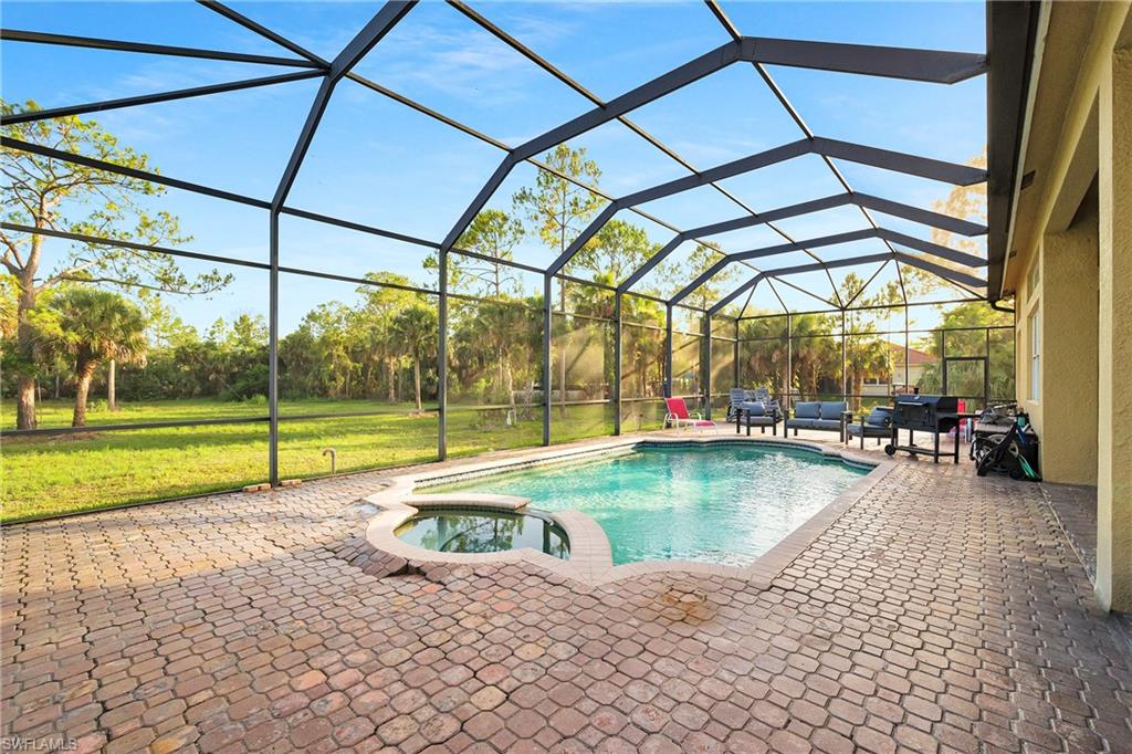View of pool with a lawn, a patio, a pool with connected hot tub, and glass enclosure