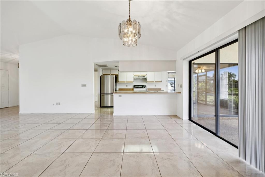 Living area with ceiling fan, baseboards, lofted ceiling, and light tile patterned flooring