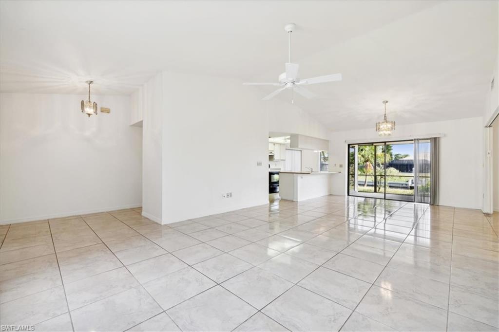 Unfurnished living room featuring vaulted ceiling and a chandelier