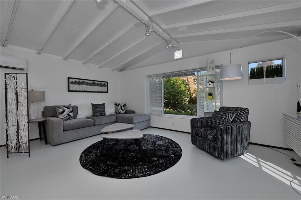 Living area with a wall unit AC, healthy amount of natural light, and finished concrete floors