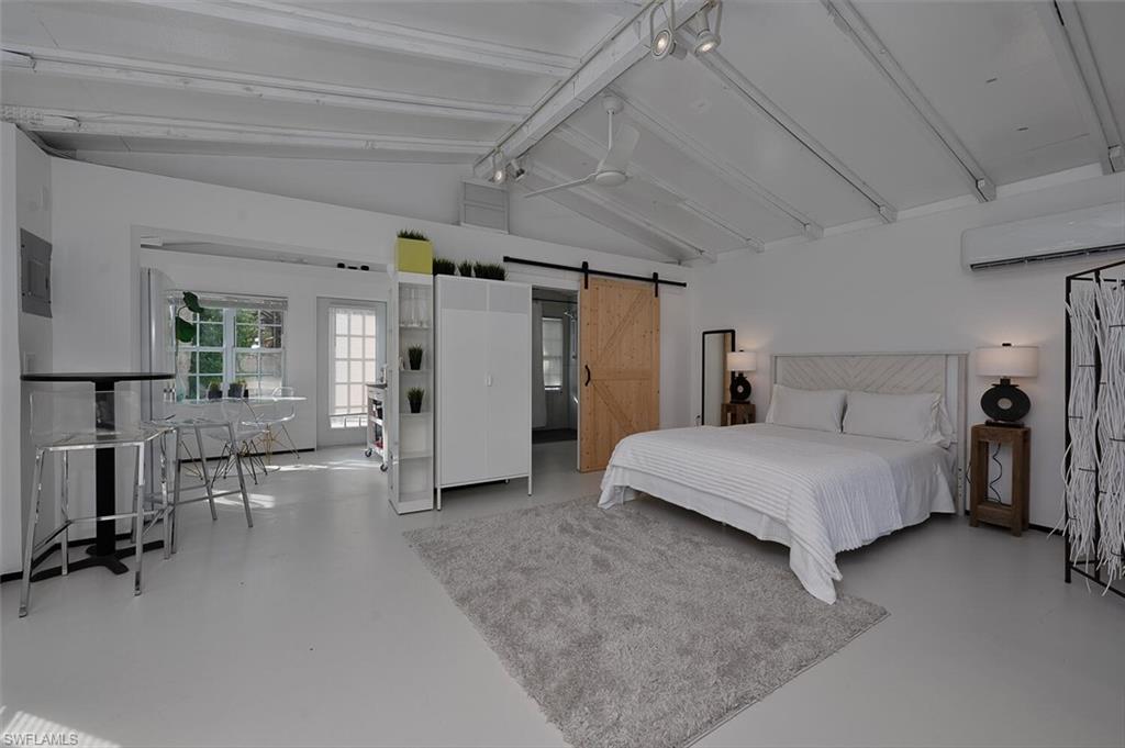 Bedroom featuring concrete flooring, a barn door, and a wall unit AC
