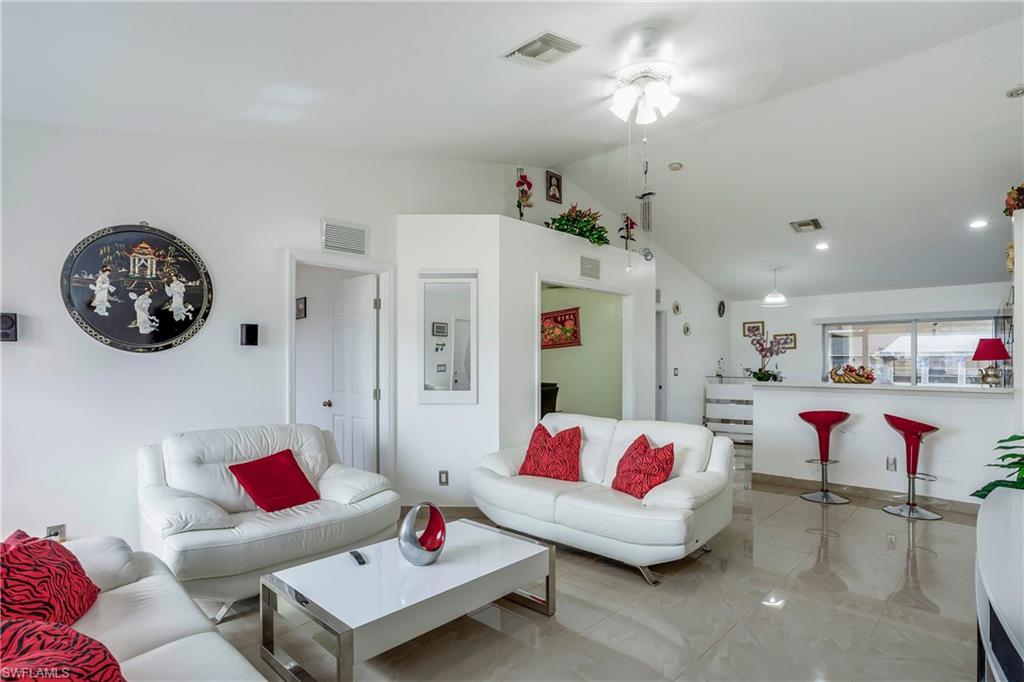 Living area featuring lofted ceiling, ceiling fan, and light marble finish flooring