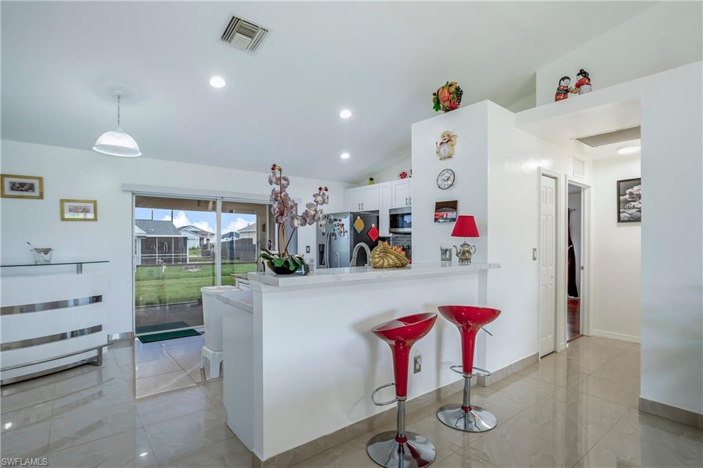 Kitchen featuring appliances with stainless steel finishes, white cabinetry, lofted ceiling, a peninsula, and light countertops