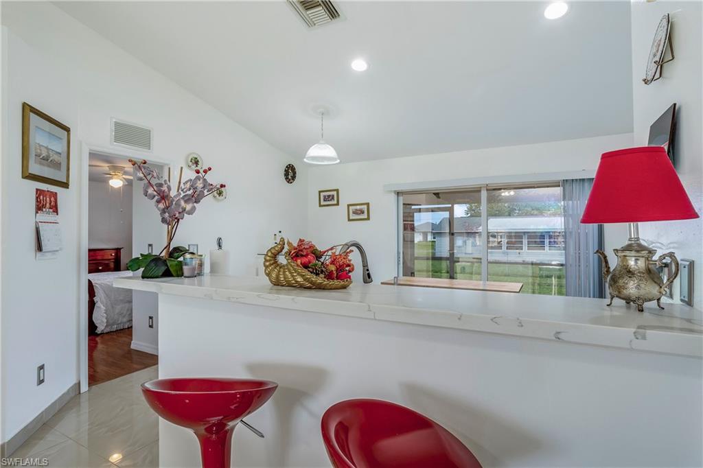 Kitchen with lofted ceiling, recessed lighting, decorative light fixtures, and baseboards