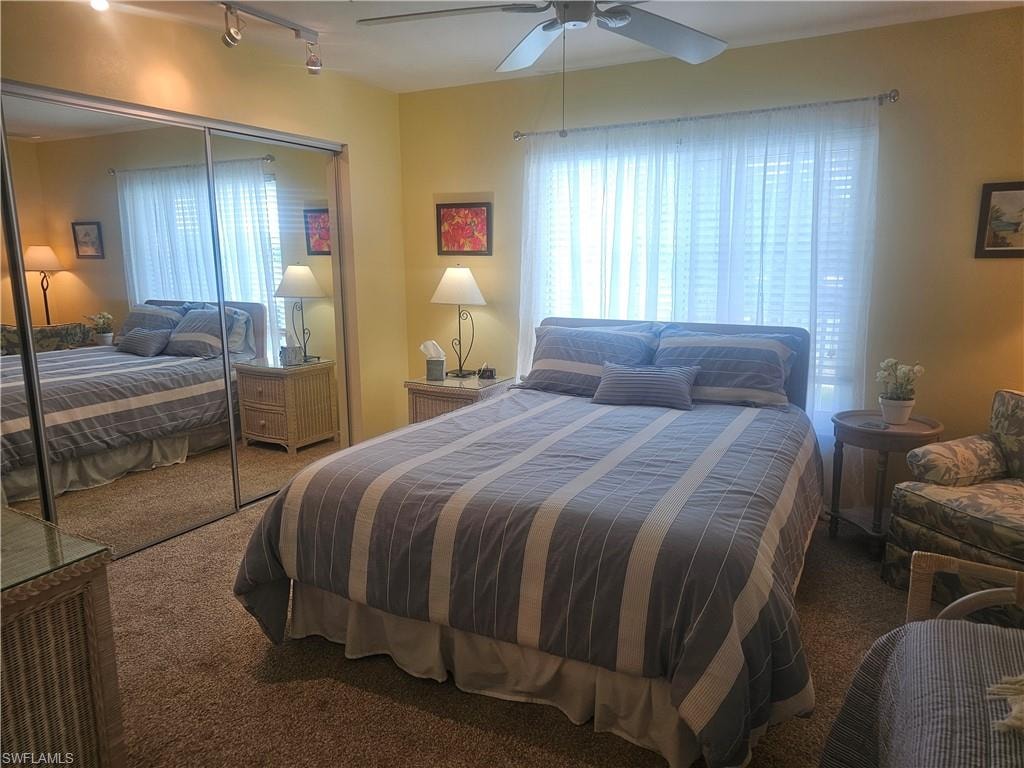Bedroom with carpet floors, a closet, track lighting, and a ceiling fan