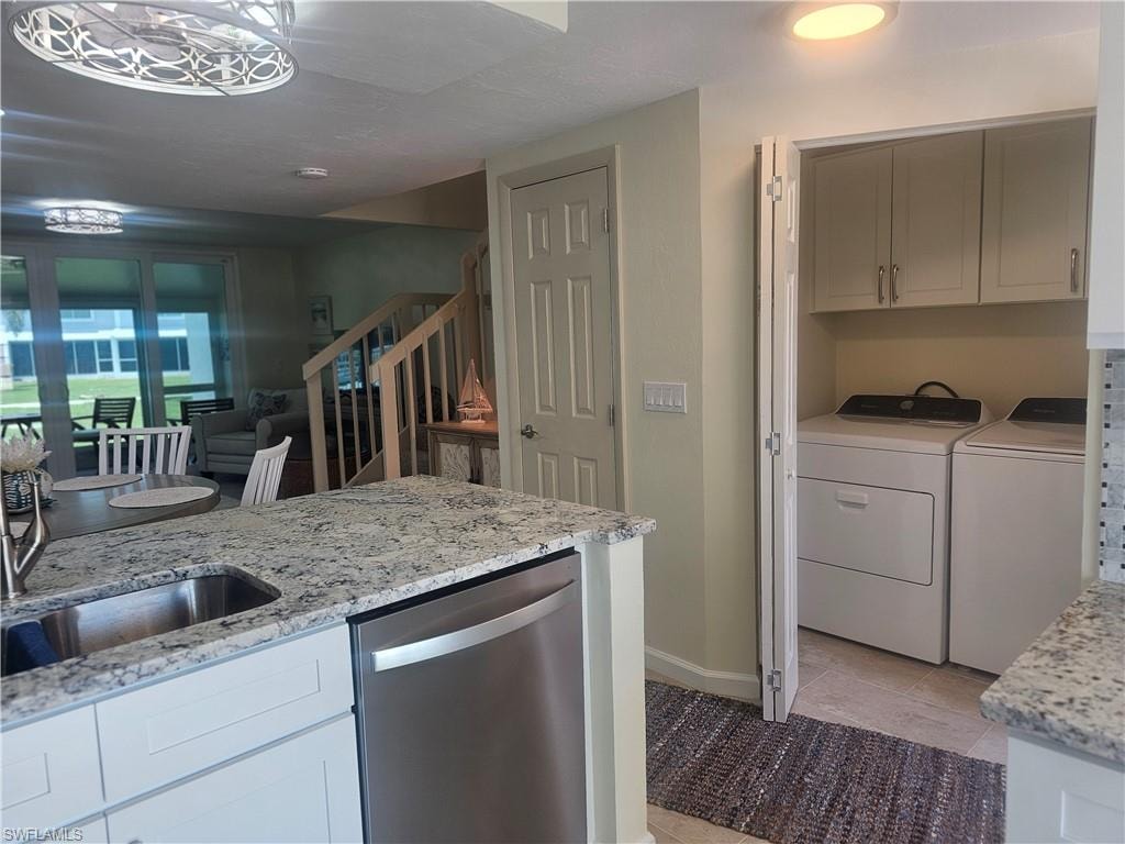 Kitchen featuring dishwasher, separate washer and dryer, light stone countertops, open floor plan, and light tile patterned floors