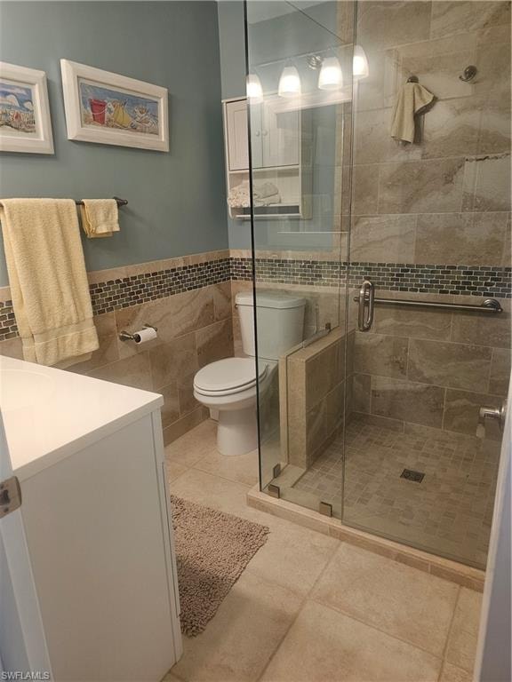 Bathroom with vanity, a stall shower, tile walls, a wainscoted wall, and tile patterned flooring