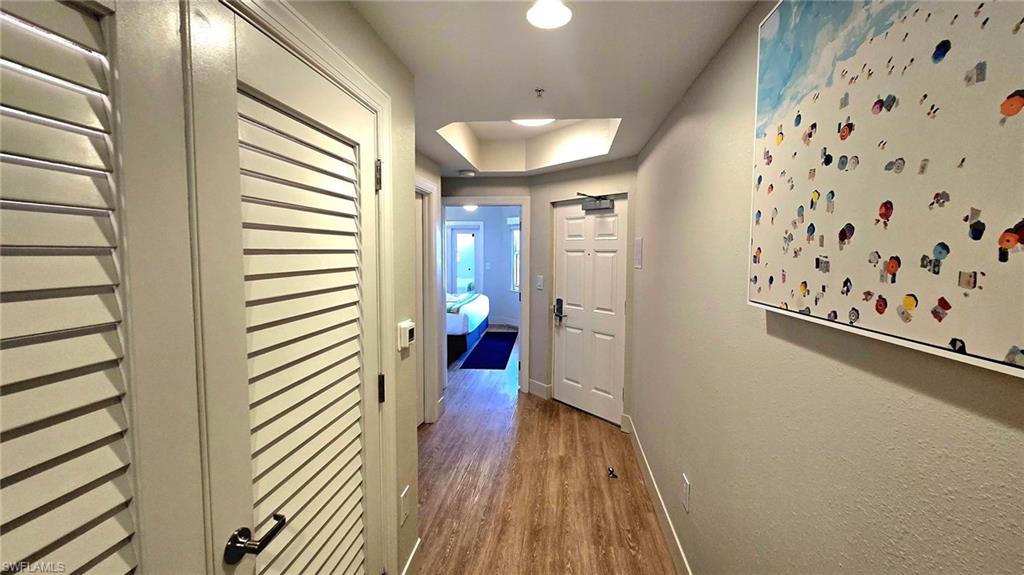 Hall featuring light wood-type flooring and a tray ceiling