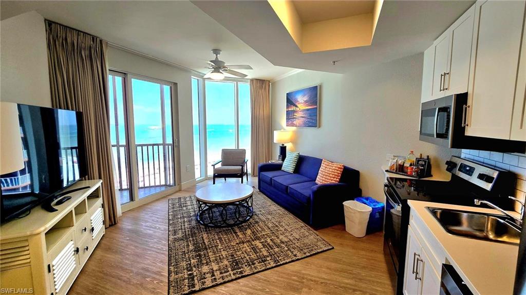 Living area featuring light wood-style flooring, a water view, and a ceiling fan