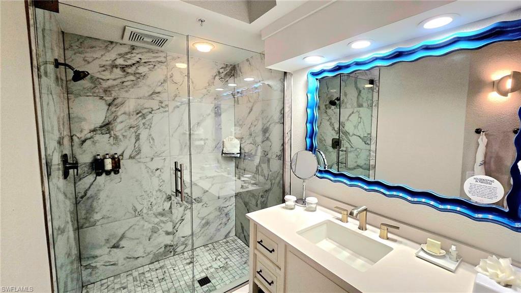 Bathroom featuring vanity and a marble finish shower