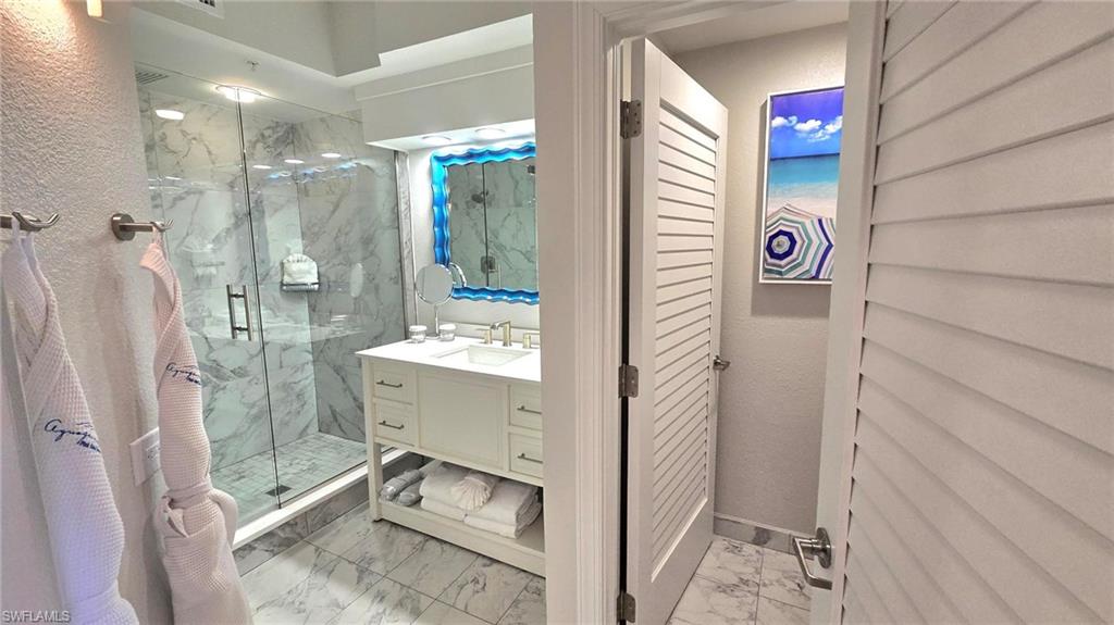 Full bathroom with marble look tile flooring, a marble finish shower, vanity, and a closet