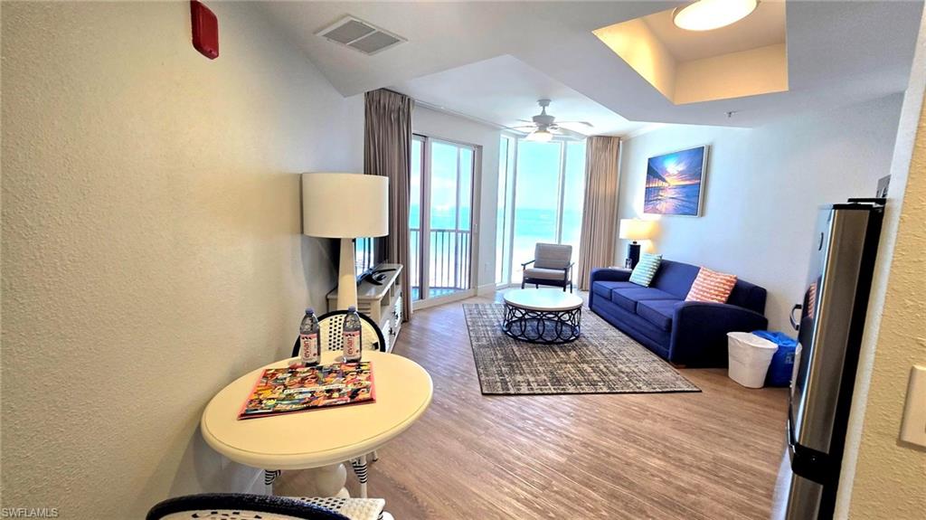 Living room featuring a textured wall, wood finished floors, and a ceiling fan