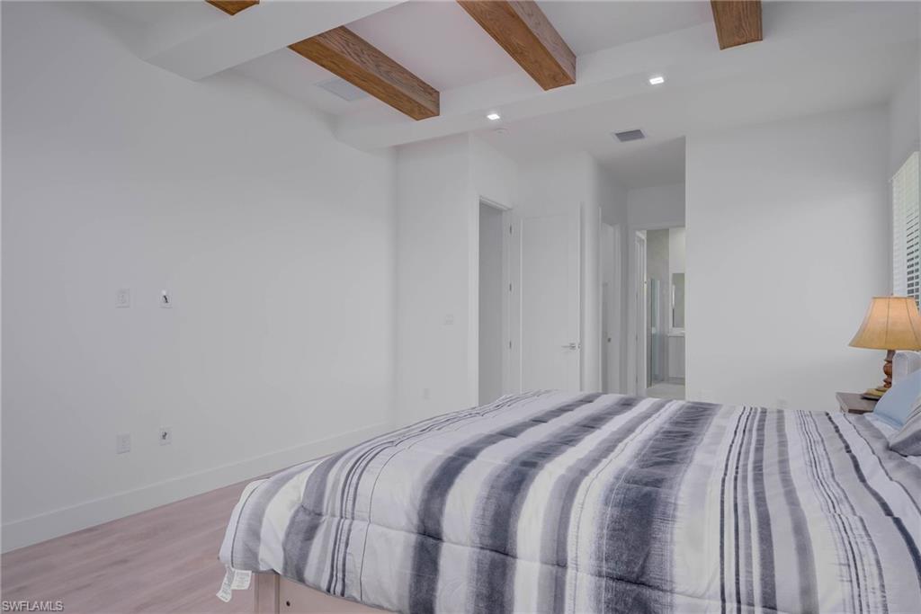 Bedroom featuring beam ceiling, light wood-type flooring, and recessed lighting
